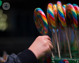 A child's hand reaching and grasping at a sugary giant lollipop