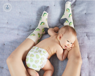 Baby crawling across mother's legs