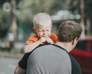 A young boy of about five years old is crying. He is being carried by his father. Any child with a sign of scrotal swelling should be taken to a paediatric urologist as soon as possible. 
