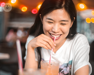 A woman smiling and drinking through a straw