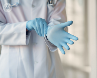 Surgeon putting on blue medical gloves