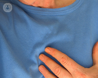 Man with chest pain, which can lead to a heart attack, with his hand on his chest