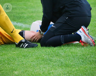 An injured footballer lying down on the pitch.