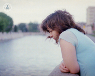 A woman looking sad while looking over the river 