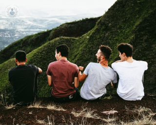 Four men sitting on a mountain laughing