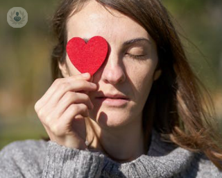 Woman with a red paper heart - the real thing can be affected by pericarditis and myocarditis