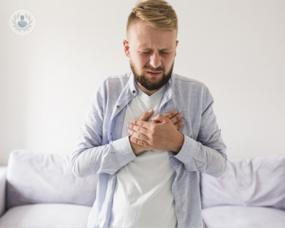 Man with heartburn, holding his hands to his chest and with a pained expression