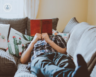 man relaxing on the sofa with a book