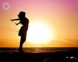 Woman standing in the sea breeze at sunset