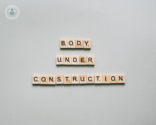 Scrabble pieces spelling out 'body under construction'