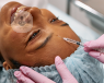 A clinician administering a facial aesthetics injection into a patient's forehead.