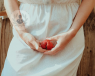 women holding strawberry in front of her genital area. Women can experience different skin conditions of the vulva.