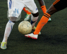 Photo of three men's legs tackling a football