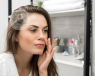 Woman looking at herself in the mirror and touching her nose