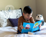 A child reading a book in bed. 