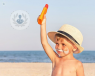 young child on the beach with a sun hat and holding sun cream