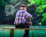 Elderly man sitting on a bench overlooking a lake
