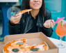 woman eating pizza and smiling 