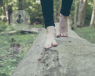 woman with bare feet walking on a log