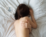 Woman in pain and holding her shoulder in bed