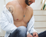 Man sat down with his shirt unbuttoned showing his chest