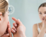 Woman putting in her contact lens in front of a mirror