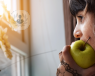 Woman eating an apple and looking out the window