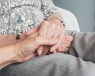 Someone holding the hands of an elderly woman