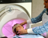 Girl lying down about to have a brain scan while a nurse supervises 