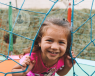 Little girl smiling next to a climbing frame in a playground