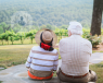 Two elderly people sat down looking at the countryside