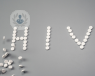 The word HIV spelt out using white tablets on a grey background