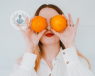 Woman placing oranges, which are good for your eye health, to her eyes