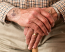 A close up of an elderly man's hands on the top of his walking stick. Many patients with Parkinson's disease require a walking aid for stability.