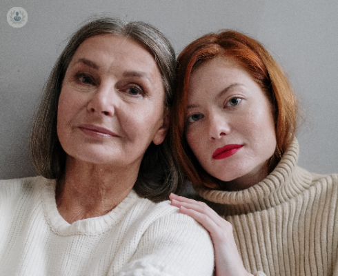 Mother and daughter with serious expressions stood against a white background