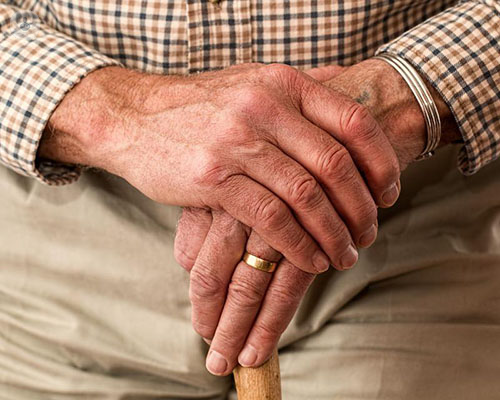 Elderly man holding a cane for support