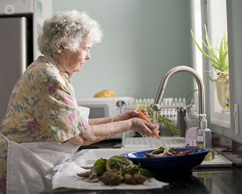 An older woman washes her hands at the kitchen sink at home. Older people are more at risk of having complications resulting from COVID-19.
