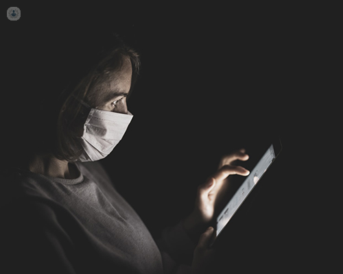 A woman wearing a covid-19 face mask uses her smartphone to use the new coronavirus test and trace system.