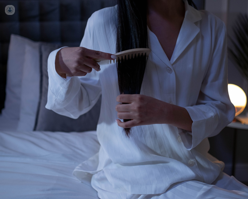 Woman with insomnia brushing her hair as a bedtime ritual to help her sleep