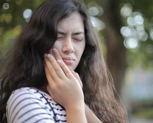 Girl stood outside in pain, holding her jaw