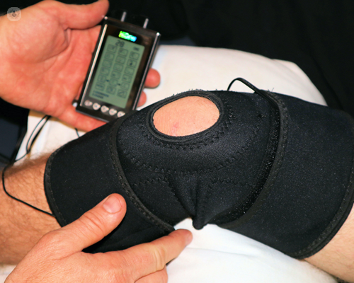Knee in a black brace, being assessed using technology