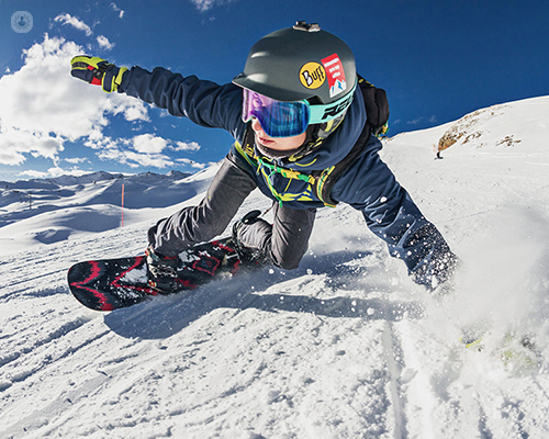 Snowboarder going down a slope. Snowboarders can be prone to certain injuries, which may benefit from PRP treatment.