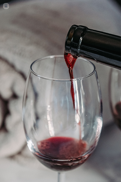 A close up of a glass of red wine being poured