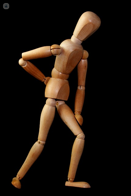 Wooden manikin model demonstrating back pain from a slipped disc