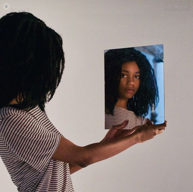 Girl with body dysmorphic disorder looking in the mirror