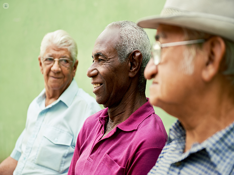 Group of three older men, who are more at risk of developing benign prostatic hyperplasia, sat together outside