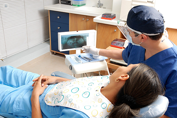 A dentist treats a patient with the apexification procedure before root canal.