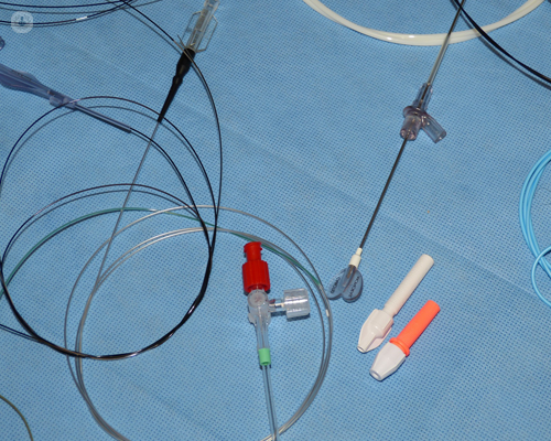 Lots of catheters on a blue cover over hospital table or bed