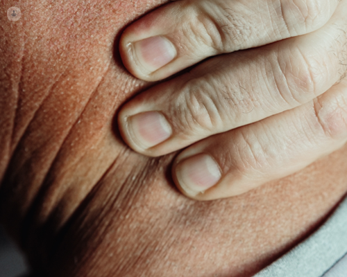 Man with neck pain putting pressure on it with three fingers