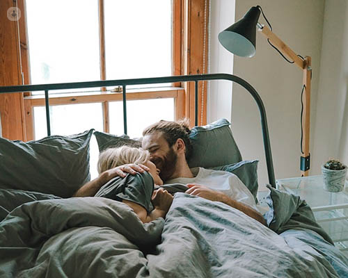 A couple in bed laughing.